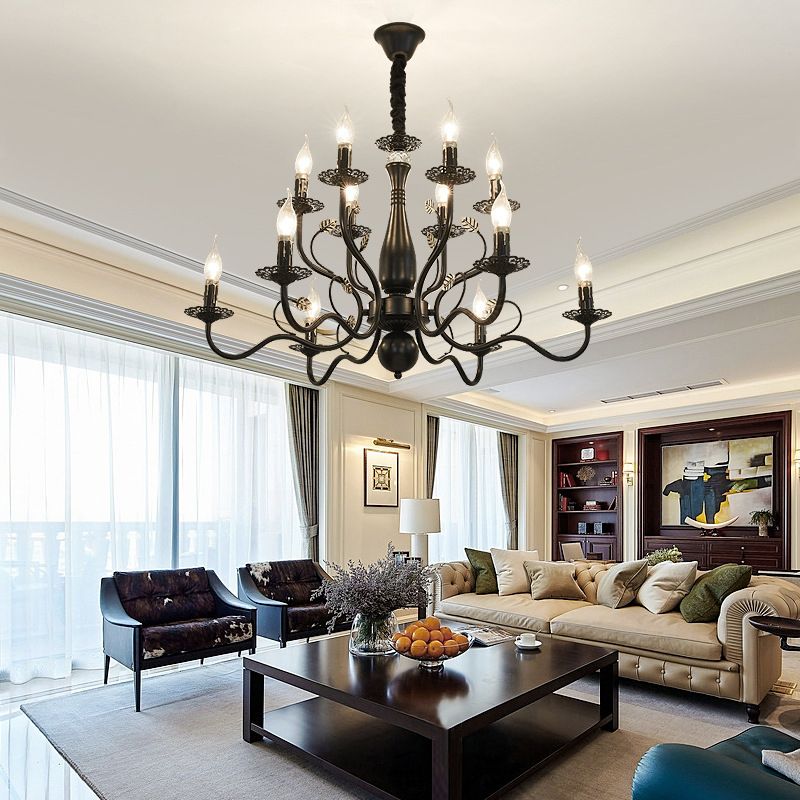 Black 12-Light Marilyn above a dark coffee table with fruit and a flower vase, between cream sofa and dark chairs near tall windows.