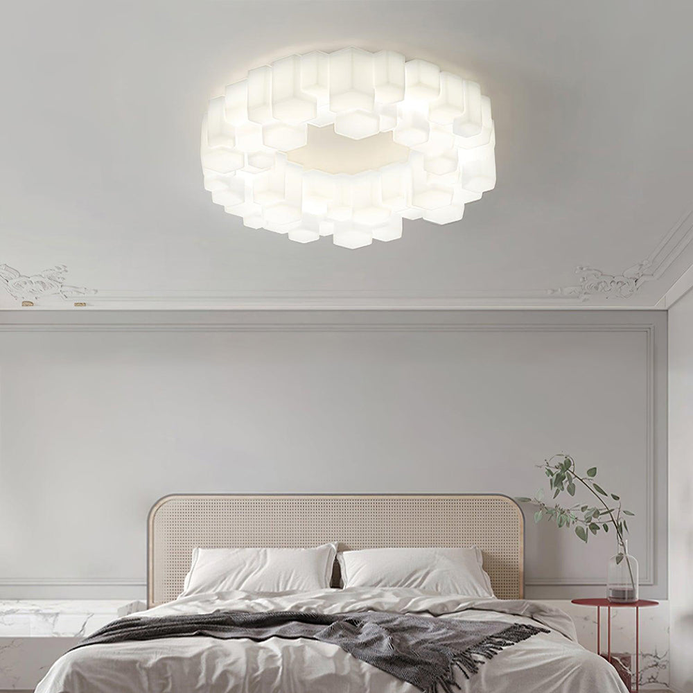 White-lit Quinn in a pale panelled bedroom with a cane headboard, gray bedding, a red round table and branches in a clear vase.