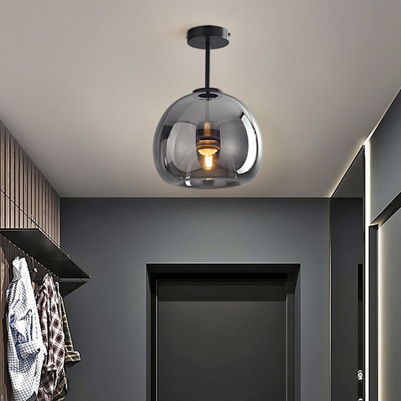 Black Sanna long-stem pendant above a dark entrance door beside wood slats, hanging coats and a mirror.