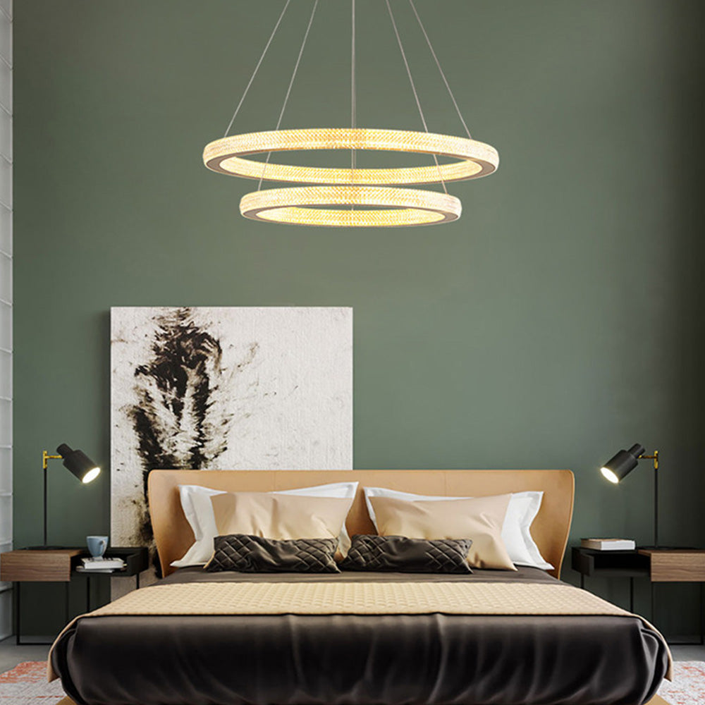 Two level Kirsten rings above bed with tan headboard and dark bedding, green wall and separate black bedside wall lights