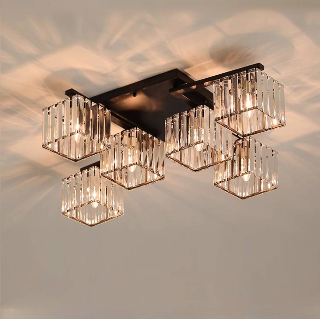 Six black-framed Kristy cube shades under crossing arms and a rectangular canopy, with lit example bulbs and warm ceiling patterns.