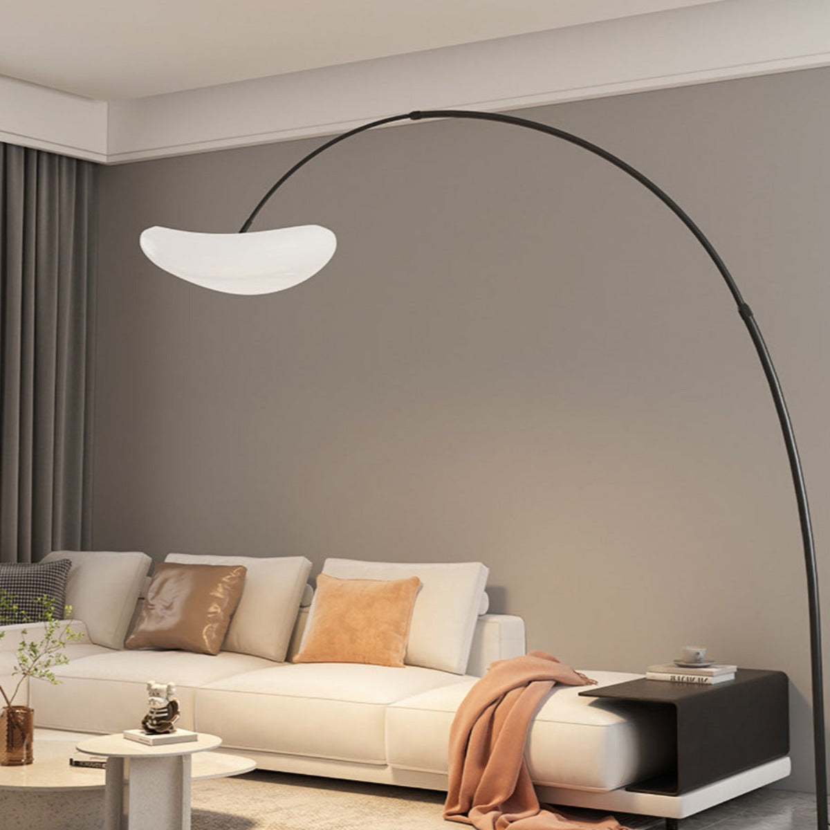 Black Minori arc floor lamp beside a white sofa and round coffee table.