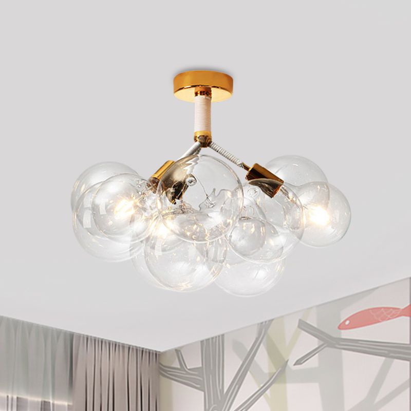 Gold-tone three-light clear globe cluster illuminated near an abstract framed picture