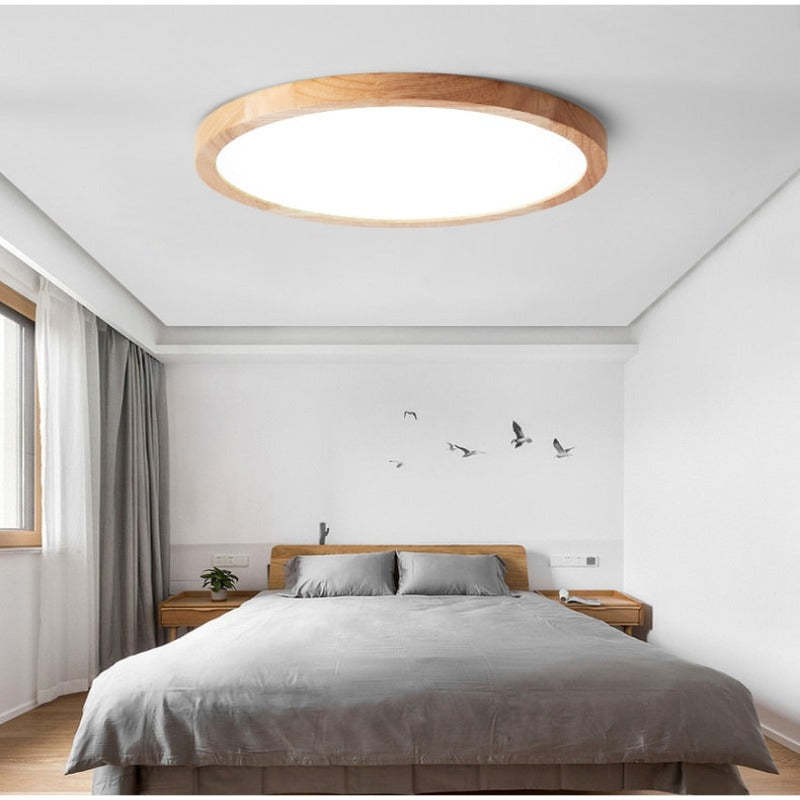 Large wood-rim Ozawa ceiling light above a bed near a window