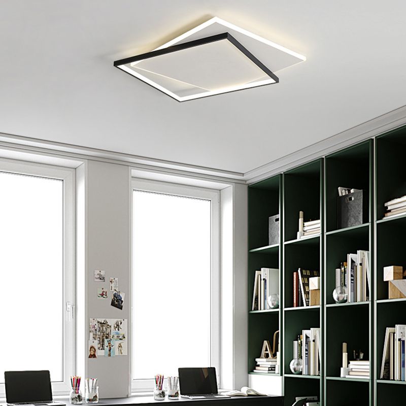Quinn black-and-white square ceiling light above a two-laptop desk beside bright windows and a tall dark green open bookshelf.