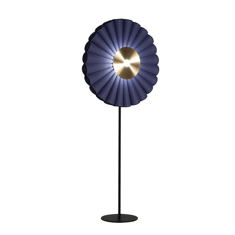 Angled view of a Blue pleated flower floor lamp with a glowing centre and black circular base on a white background