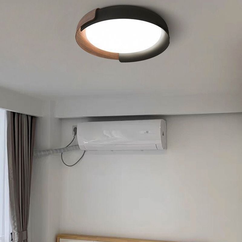 Wood-tone and black Quinn ceiling light above a wall air conditioner and wood-trimmed padded bedhead beside full-height curtains.