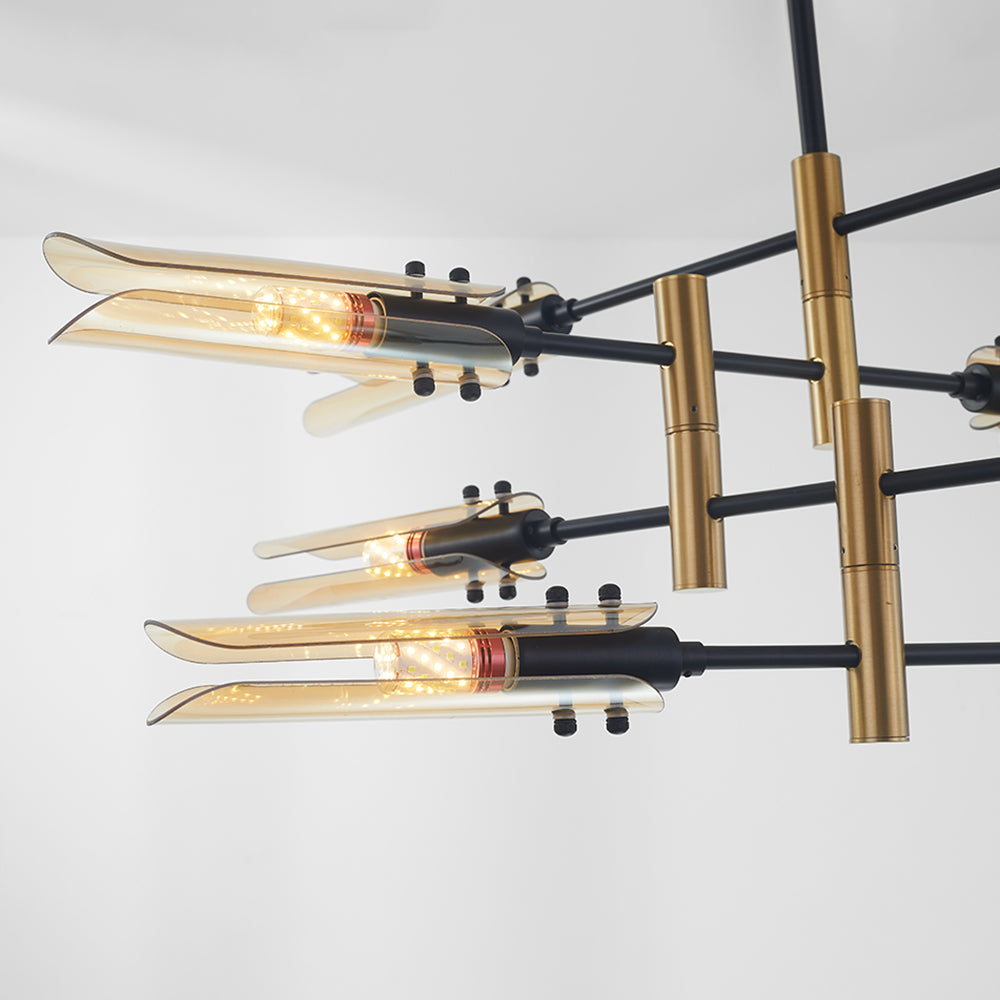 Close-up of three lit Amber Sanna glass heads on black bars beside gold-tone cylindrical joints; remaining fixture cropped.