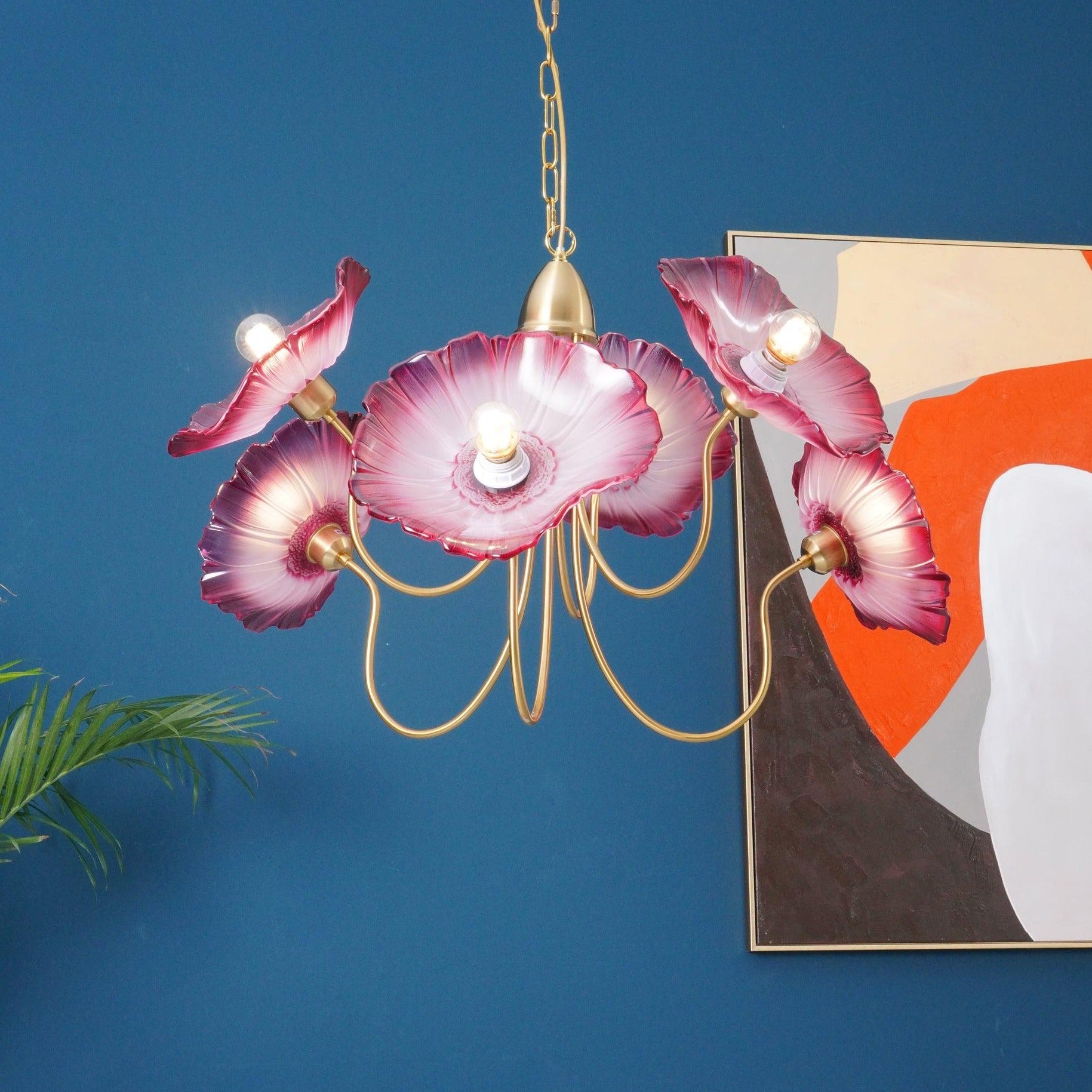 Illuminated pink flower chandelier near artwork