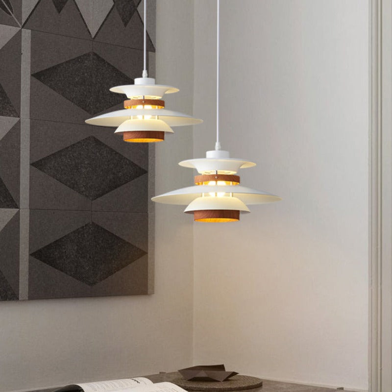 Two white layered pendants with brown wood-grain rings hanging at different heights beside geometric wall art