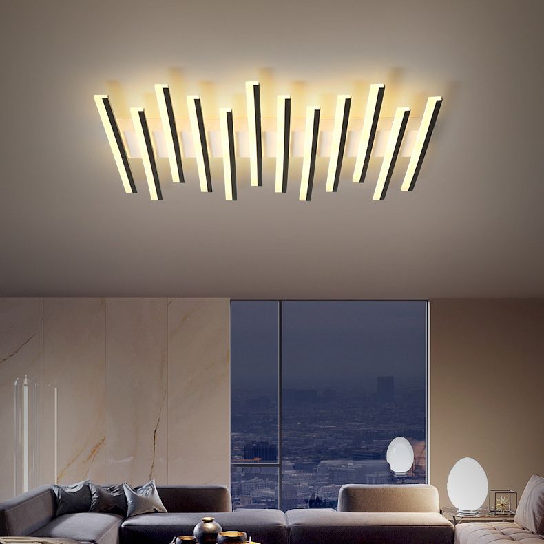 Lit Quinn piano-key-style fixture above a gray corner sofa beside a tall city-view window and separate oval room lamps.
