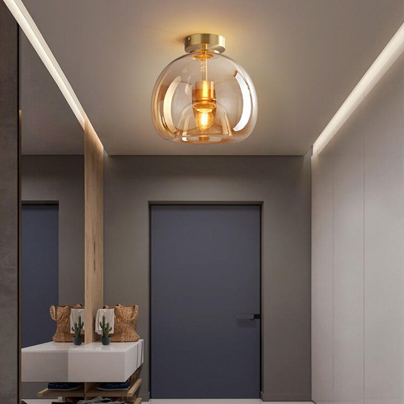 Gold Sanna ceiling light in a grey entrance with dark door, mirror, wood post, white console, cactus and woven bags.