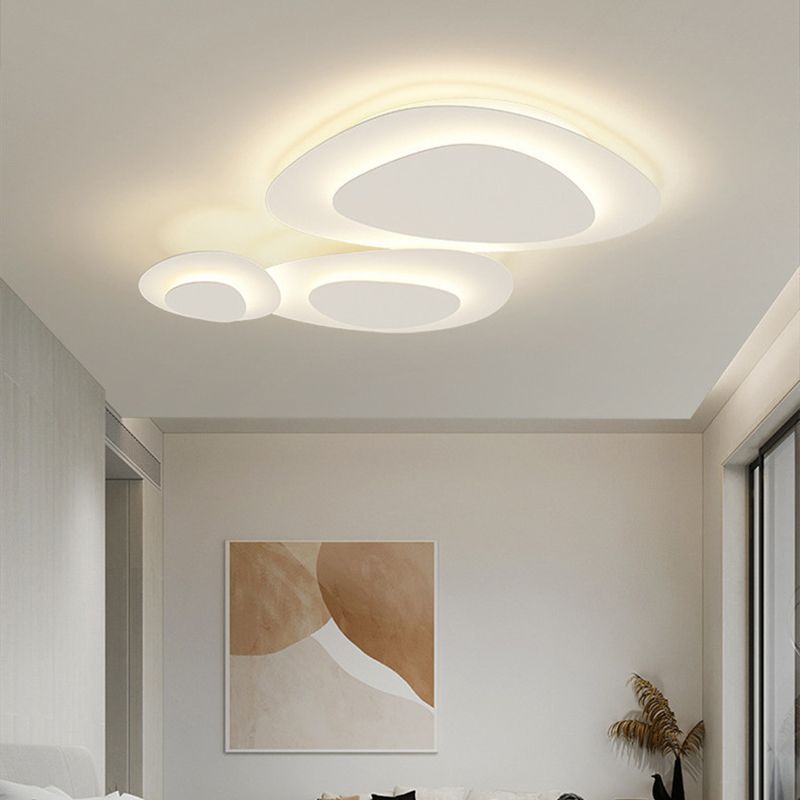 Lit Valentina oval sections above abstract tan-and-white artwork, a pale sofa edge, window and vase of dried foliage.