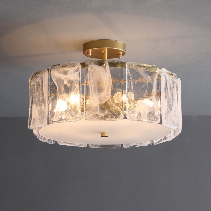 Kirsten glass-panel ceiling light with lit example bulbs, white swirls, gold-toned canopy and pale bottom plate against grey.