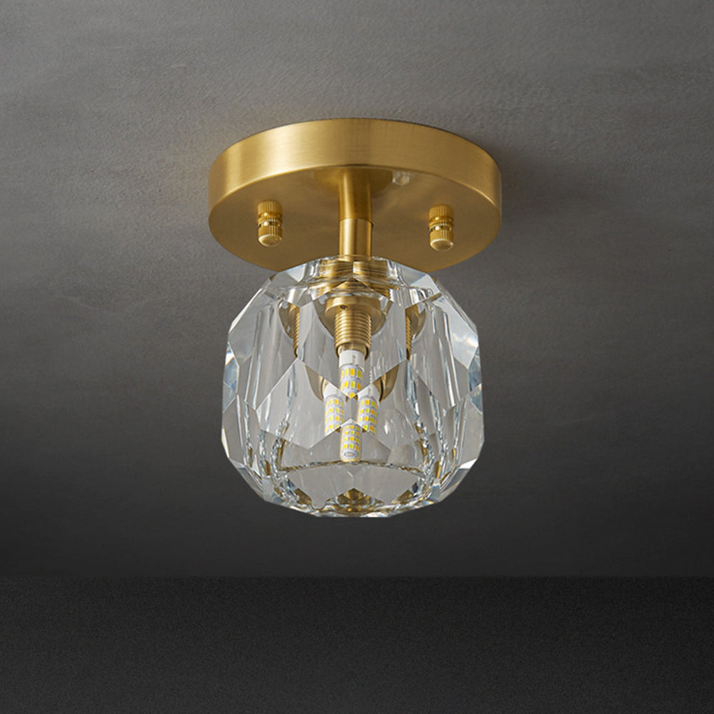 Unlit-looking Kirsten light below a grey ceiling, with clear facets, visible central LED details and gold-tone plate.