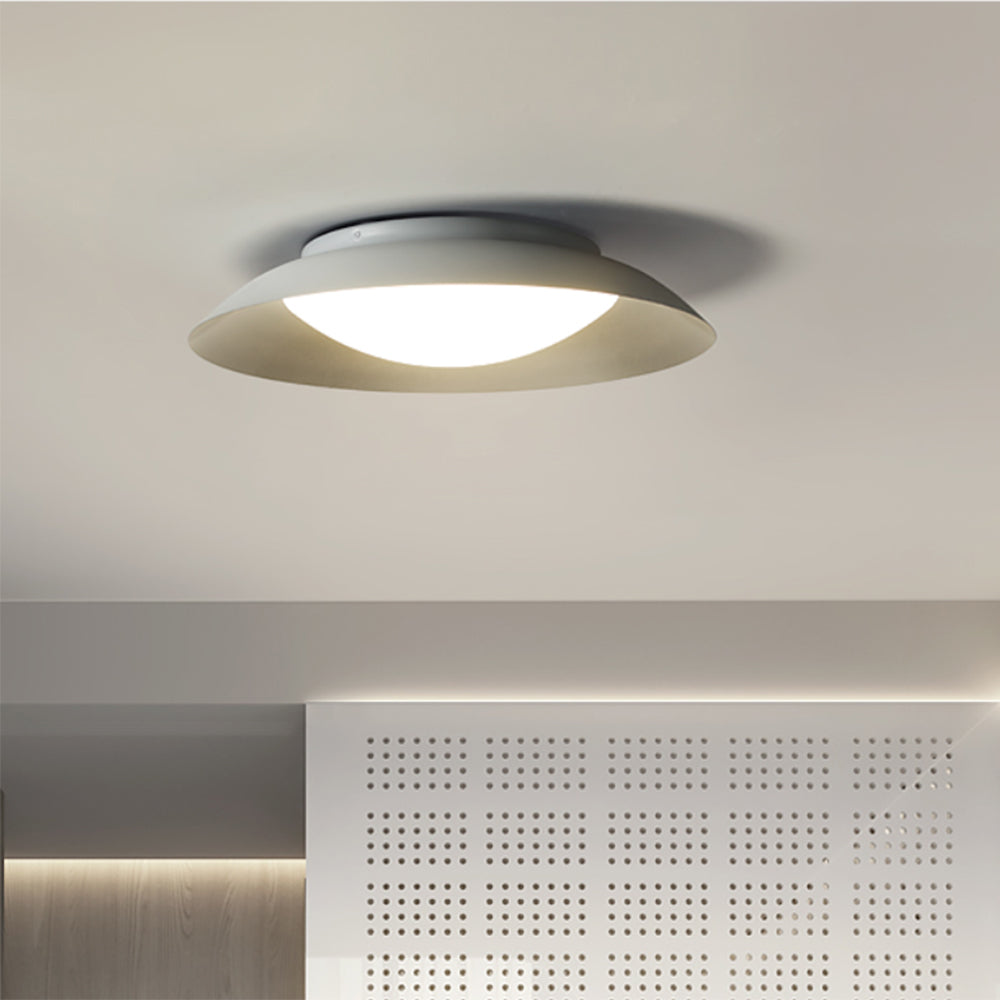 Carins lit white bowl ceiling light above a perforated white wall panel, wood strips and separate cove lighting.