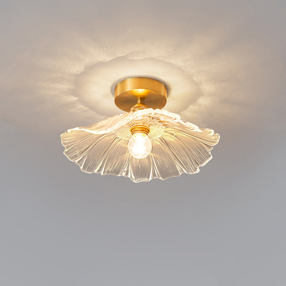 Clear Carins ceiling light close-up on grey background with short gold-tone stem, round canopy and fluted flower glass.