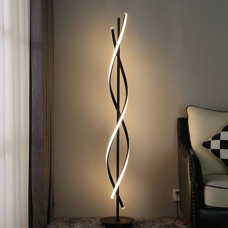 Black Louise floor lamp glowing beside a curtain and armchair, with a power cable near the wall outlet