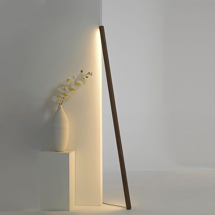 Dark wood bar glowing against a room corner beside an orchid vase on a white pedestal, with cable at floor level
