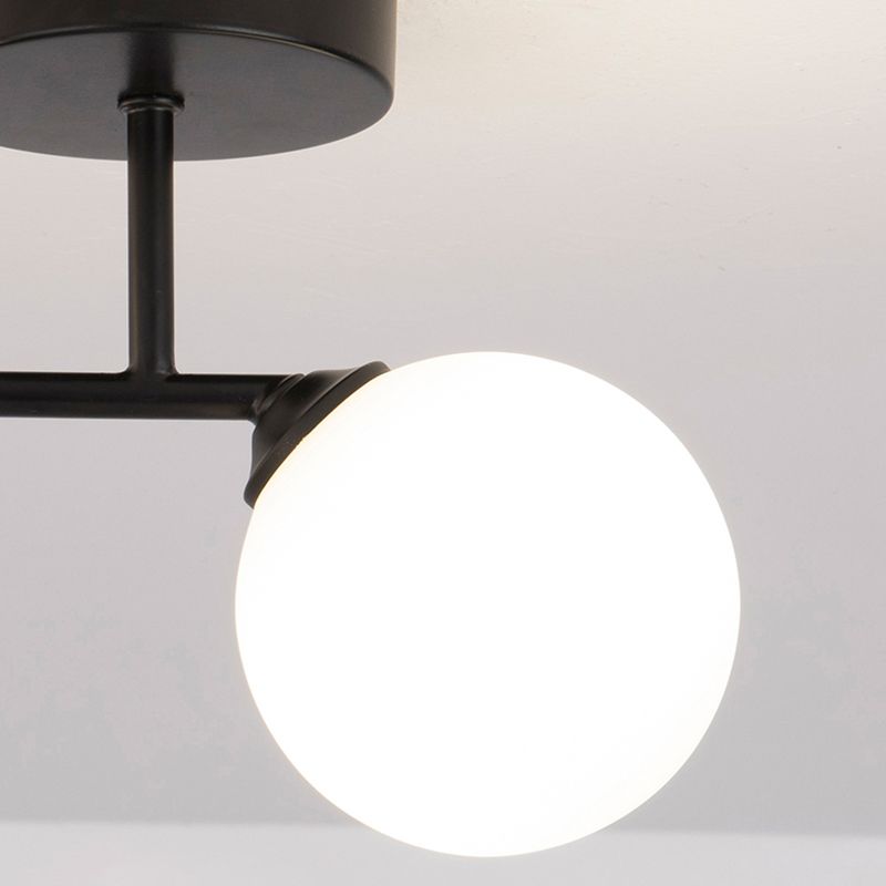 Black Valentina canopy underside, short stem, crossbar and tapered collar beside a brightly lit white globe.