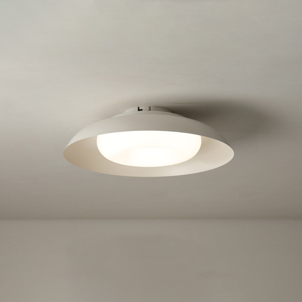 Carins lit white bowl beneath a pale ceiling, with the bright convex centre and a small fitting on the top plate visible.