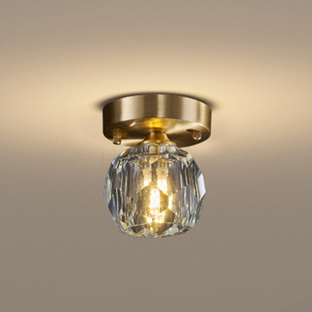 Kirsten gold-tone ceiling plate and clear faceted shade against a pale ceiling, with warm-looking central illumination.
