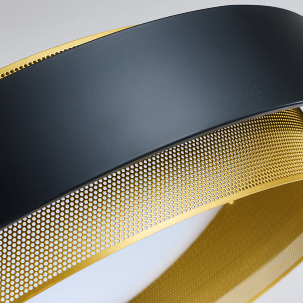 Detailed diagonal view of the black outer ring and rows of round holes in the gold-tone inner ring.