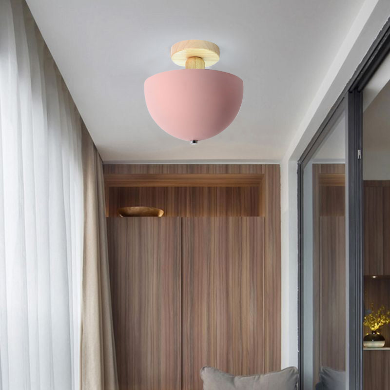 Pink Ozawa Bowl ceiling light with rounded underside and small finial, wood wall, sheer curtain, dark glass and gray cushion