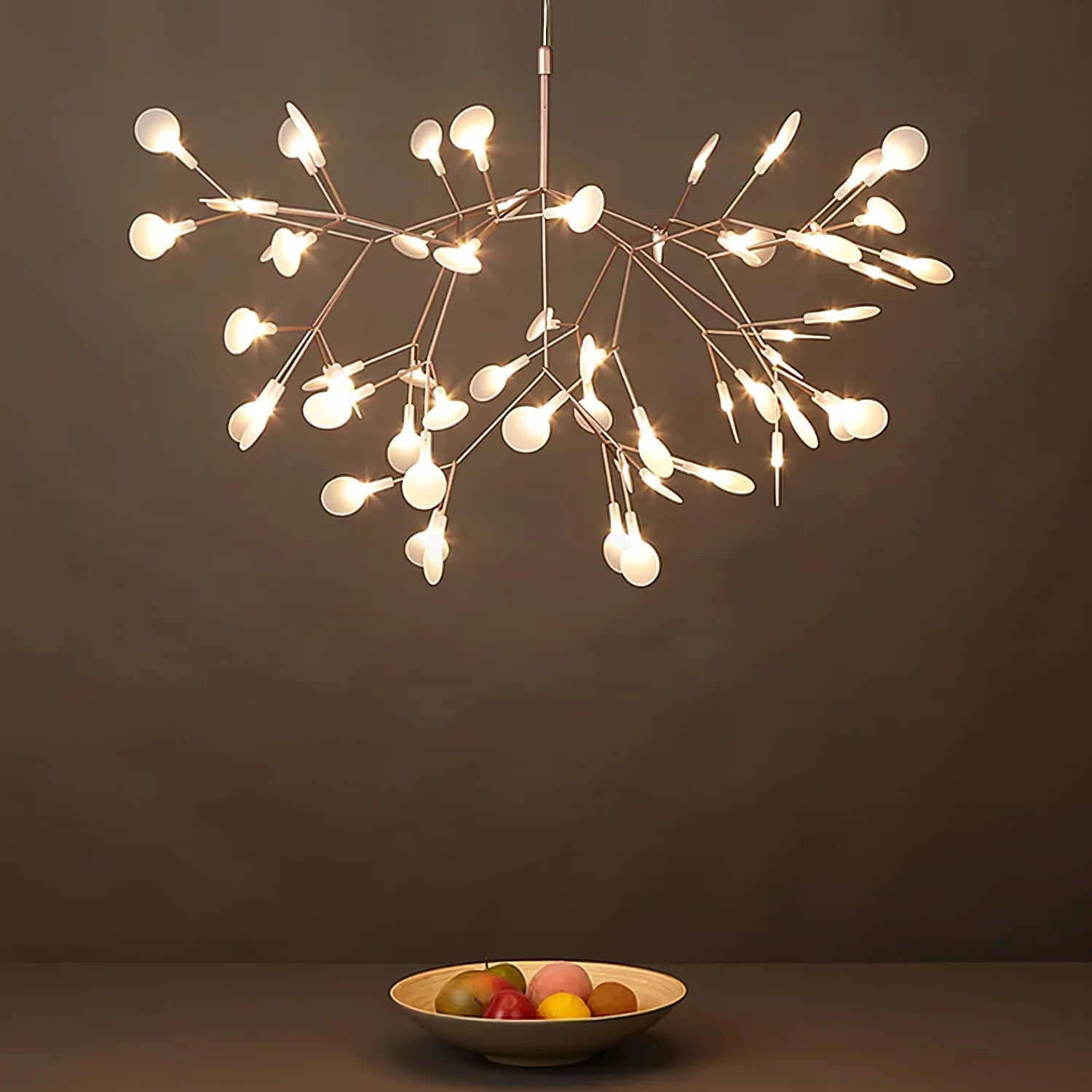 Illuminated rose-colour branches above a fruit bowl