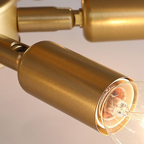 Close-up of a gold-toned Kirsten cylindrical bulb holder and lit example bulb, with its connecting arm behind.