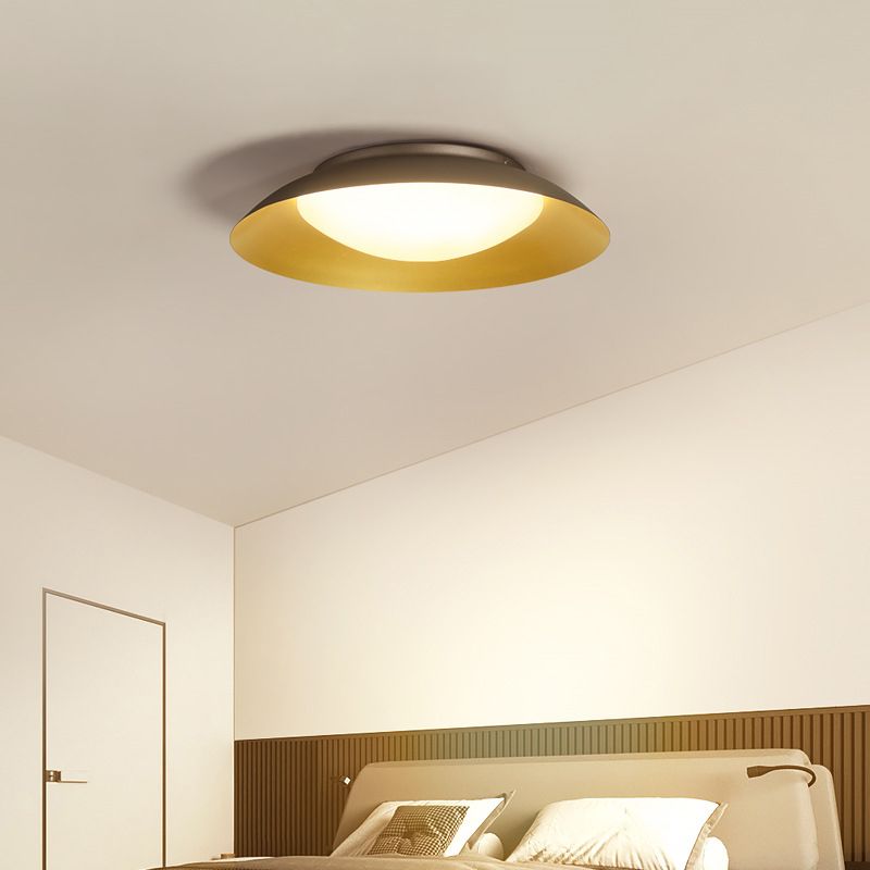 Carins lit ceiling light above a pale headboard, ribbed wood wall panel and gold-toned cushion beside an outlined door.