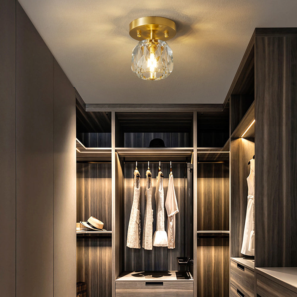 Gold-tone Kirsten light in a dark-wood wardrobe with hanging dresses, lit shelves, white handbag and straw hat.