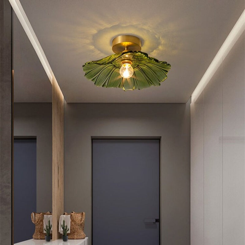 Green Carins ceiling light above a dark grey cabinet, console with cactus vase and woven bag, and mirror to the left.