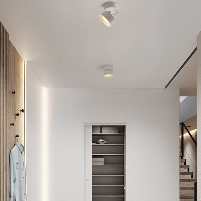 White Novak heads in a hallway beside a wood slat coat wall, blue coat, shelving and a glimpse of stairs.
