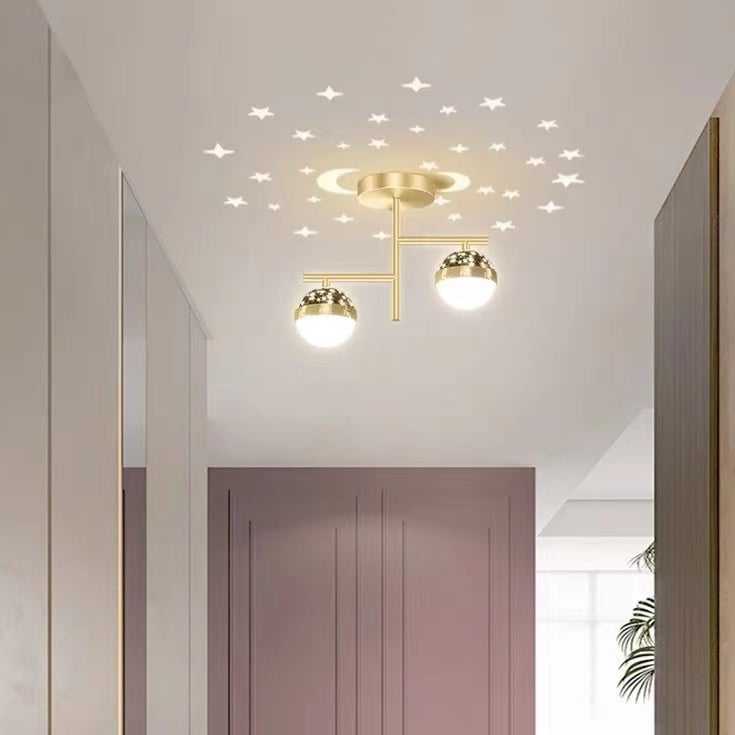Gold-frame Madina globe ceiling light above rose-colored paneled double door, with window, plant and illustrated stars and moon
