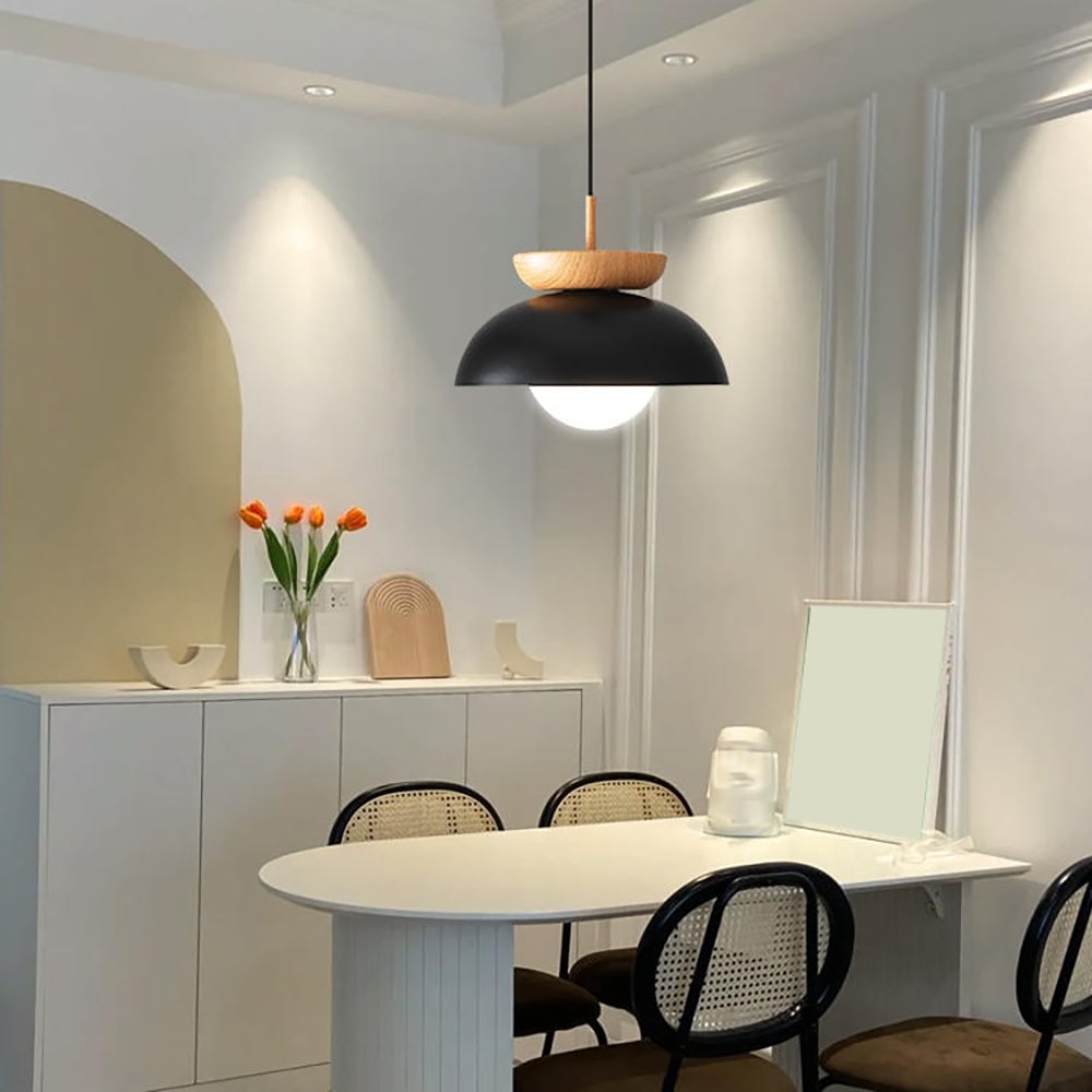 Black Ozawa pendant above an oval white dining table with cane chairs, a cabinet and orange tulips
