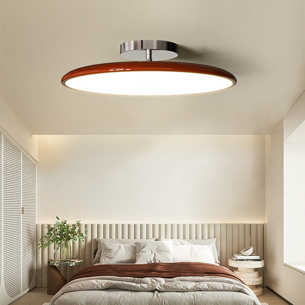 Red Valentina disc ceiling light above a bed with muted red bedding.