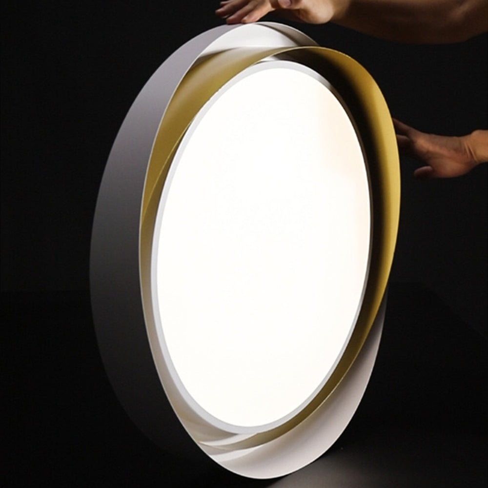 Person holding a glowing white and gold Quinn fixture vertically against a dark background, with hands beside the crossing rims.