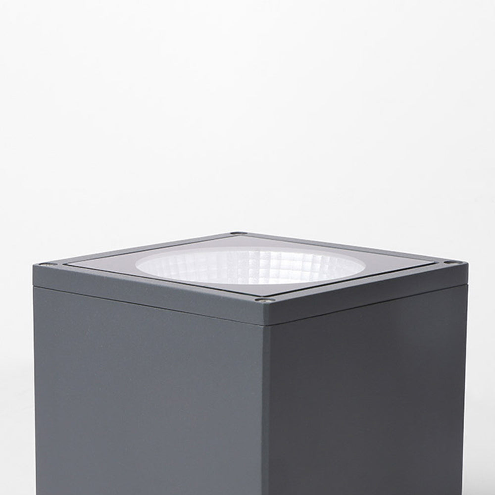 Orr close-up of dark flat body panels, square face-frame seam and edge of a recessed pale circular reflector.