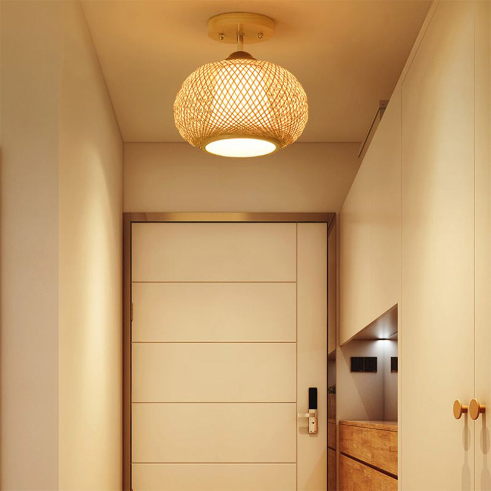 Muto lit woven ceiling light above a panelled entrance door, beside pale cabinets and wooden drawers.