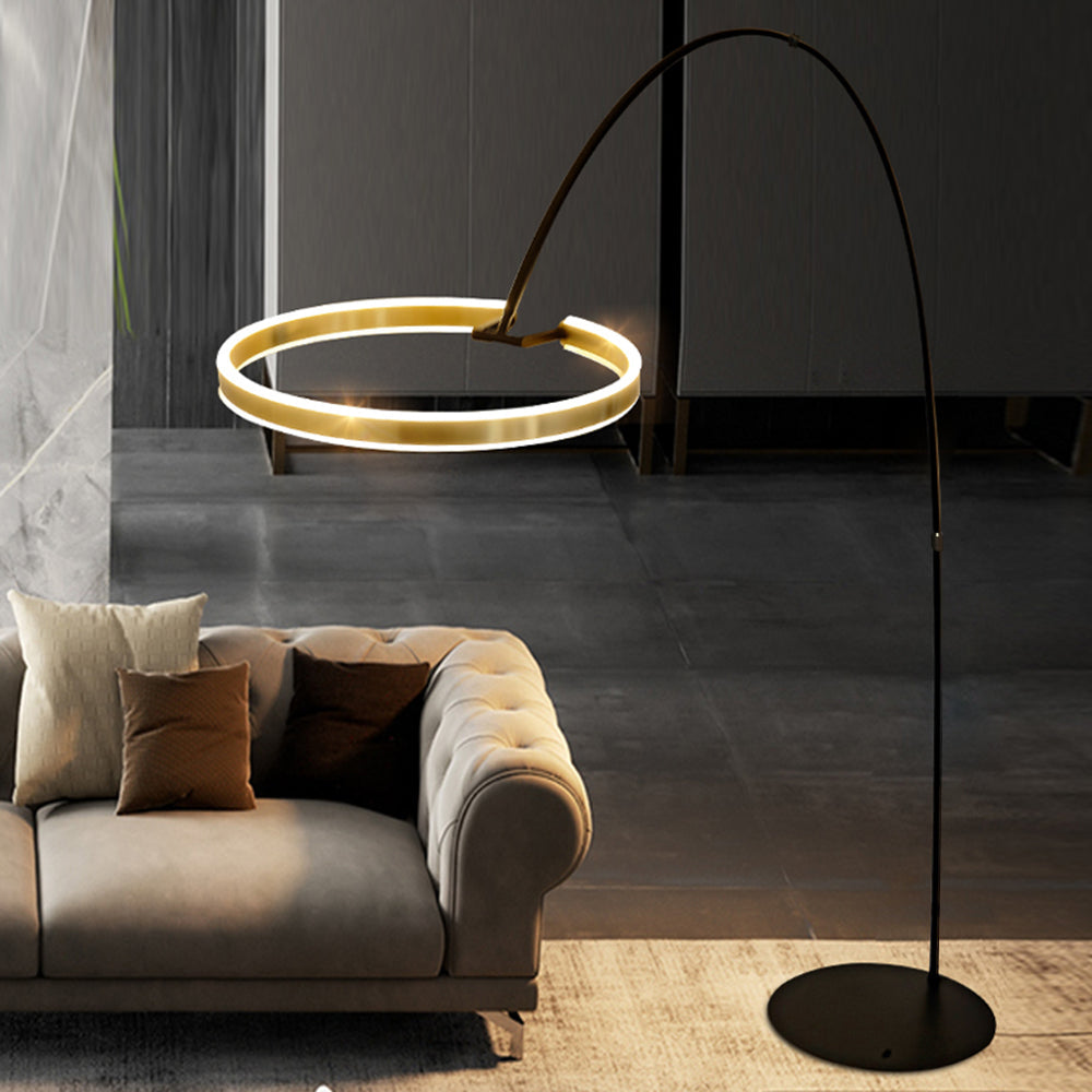 Edge illuminated ring, arched stem and round base beside a gray sofa