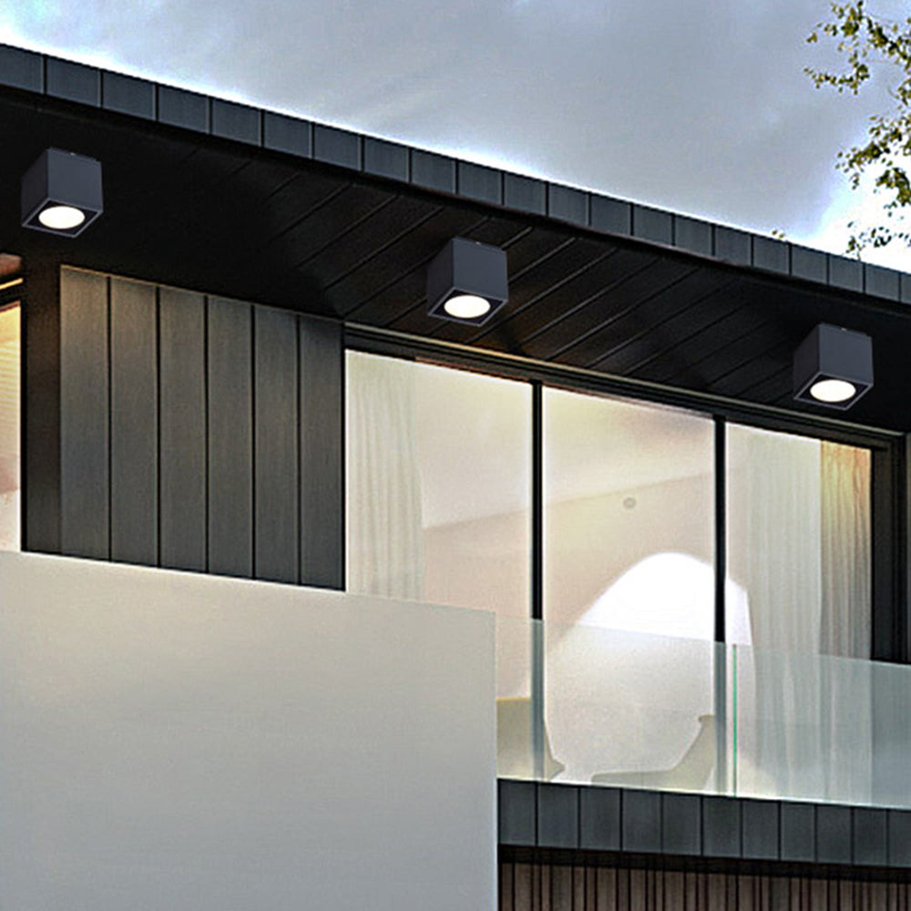 Black Orr cubes beneath a dark exterior eave above dark cladding and a large glazed window with a white curtain.