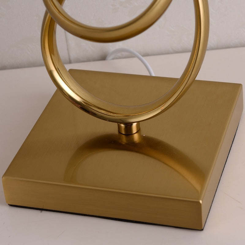Close-up of the square gold-coloured table-lamp base and looped stem