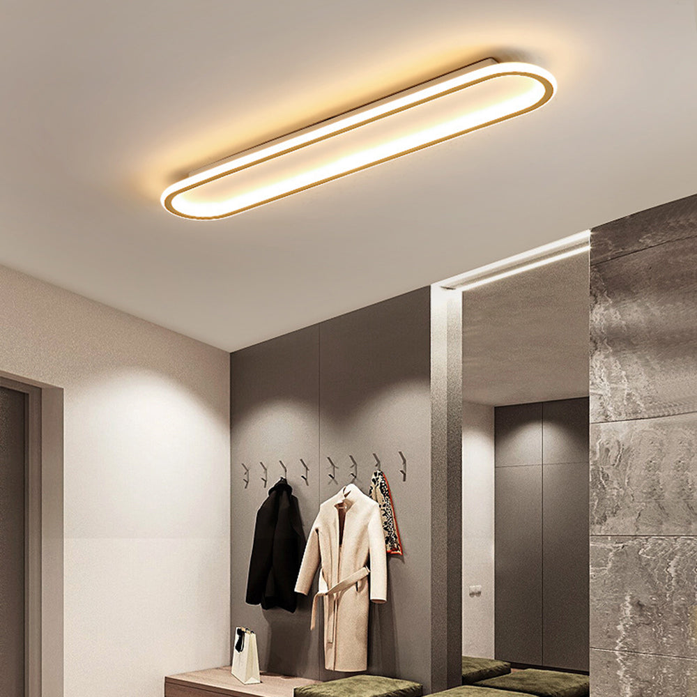 Gold Quinn light above coat hooks, dark jacket, cream belted coat, patterned scarf, mirror and stone-textured wall.