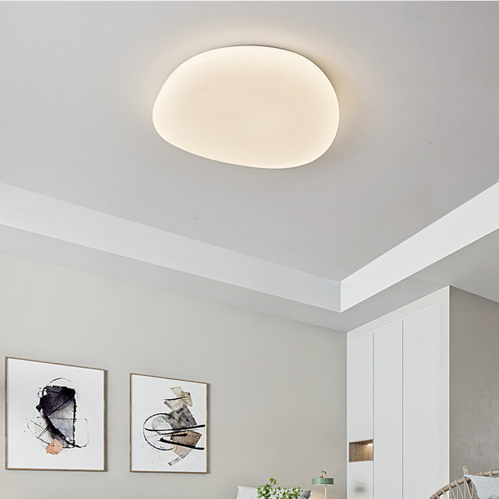 Quinn small-size ceiling light above two abstract framed prints, a white cabinet, green lamp and woven headboard corner.