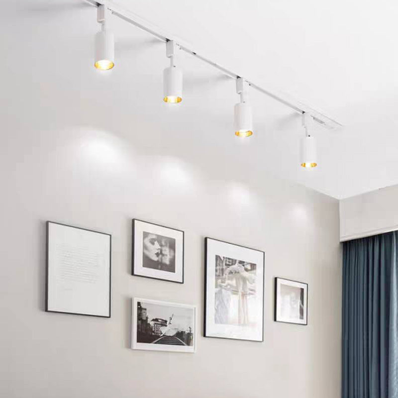 White Freja track with four visible illuminated heads above a gallery wall of framed photographs beside blue-grey curtains.