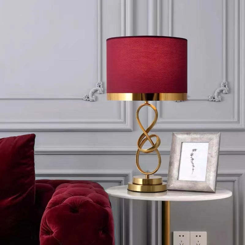 Red-shade table lamp with a round stepped base beside a sofa