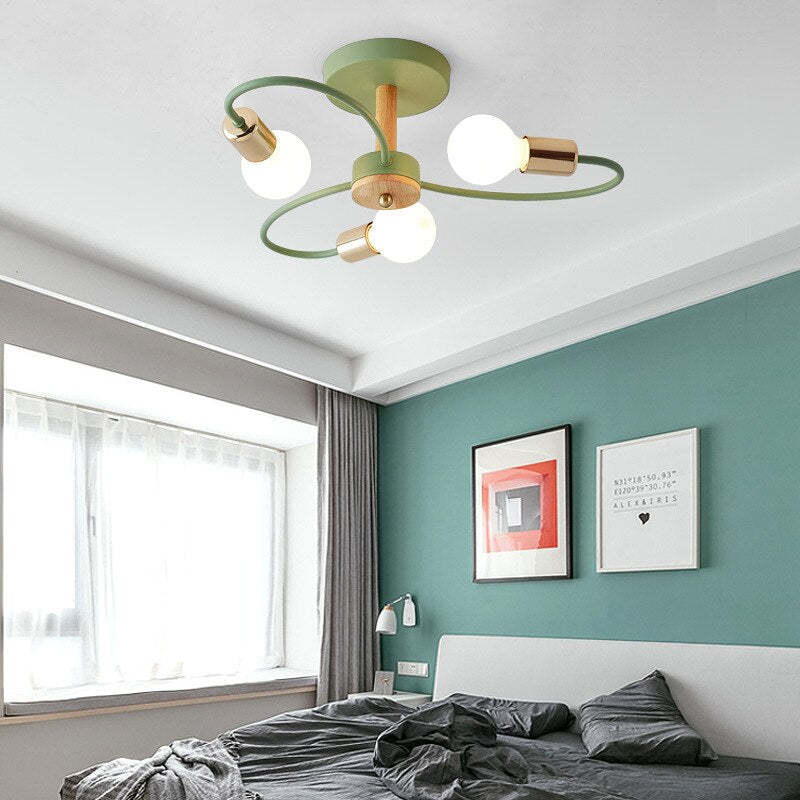 Green three-head ceiling light with looped arms above a grey bed and teal wall with framed artwork