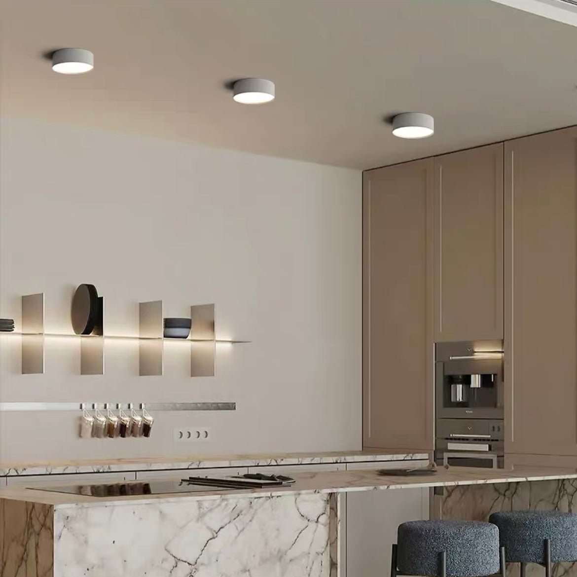 Gray Quinn ceiling lights above a marble-patterned island, near taupe cabinetry, built-in appliances, shelves and stools.