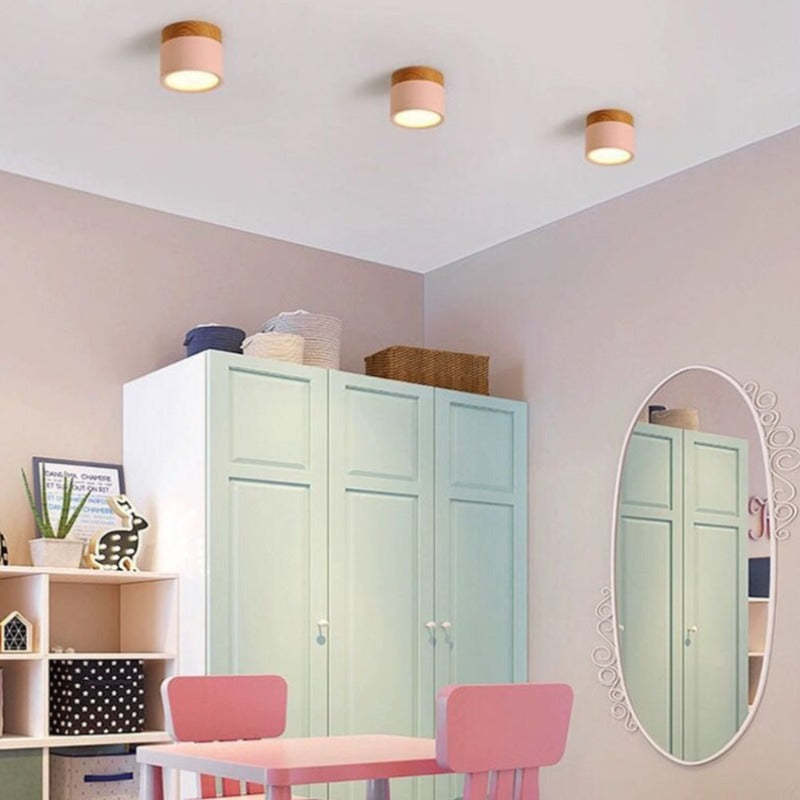 Three pink Morandi cylinders over mint wardrobes, wicker baskets, an oval mirror and pink table and chairs.